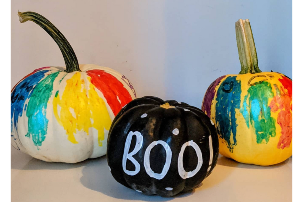 three pumpkins painted in assorted colors